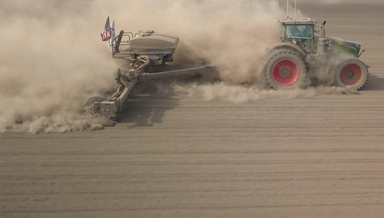 tractor pulling a planter through a dusty field