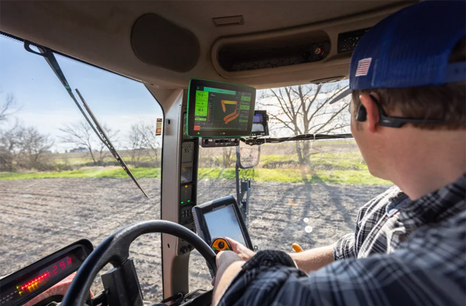 farmer in the cab of a sprayer looking at the monitor